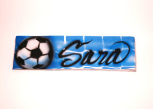 A soccer ball with the name sara written in graffiti.