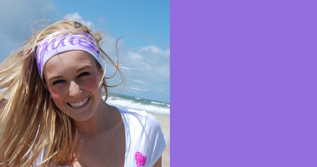 A woman with purple hair and a headband on the beach.